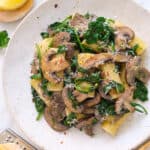 Top view of a white plate full of spinach mushroom pasta.