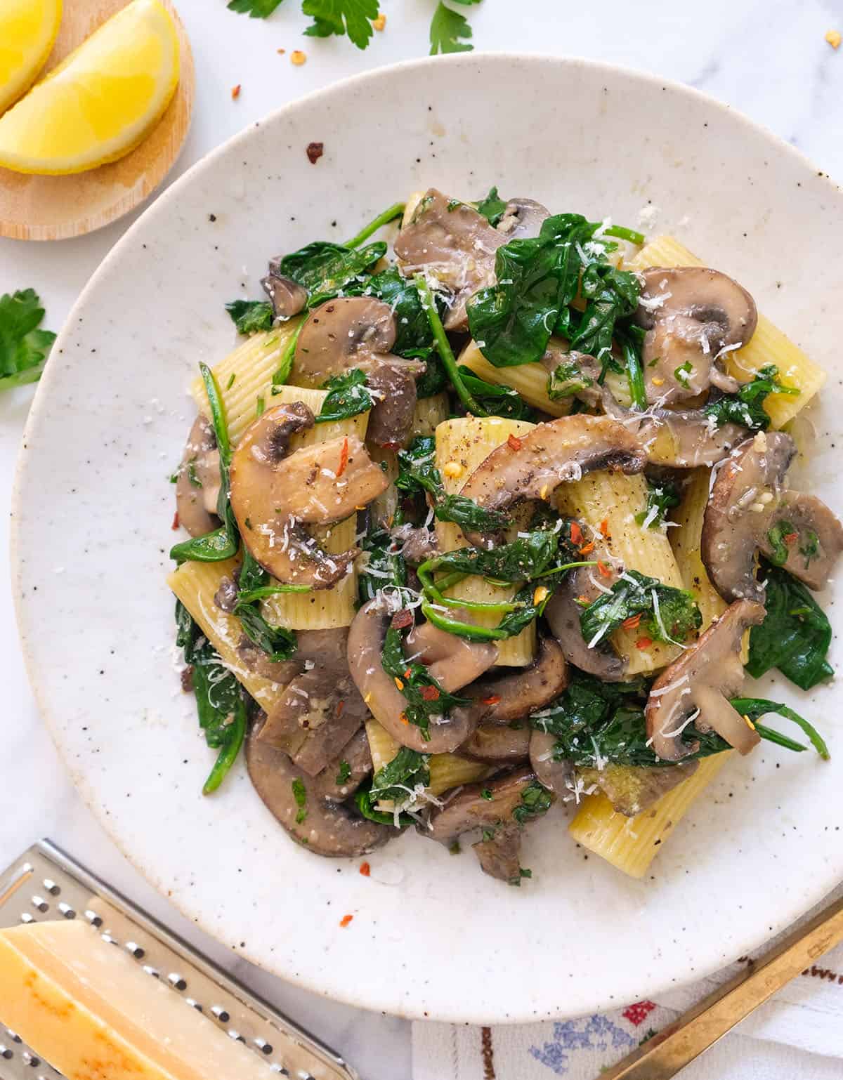 Top view of a white plate full of spinach mushroom pasta.