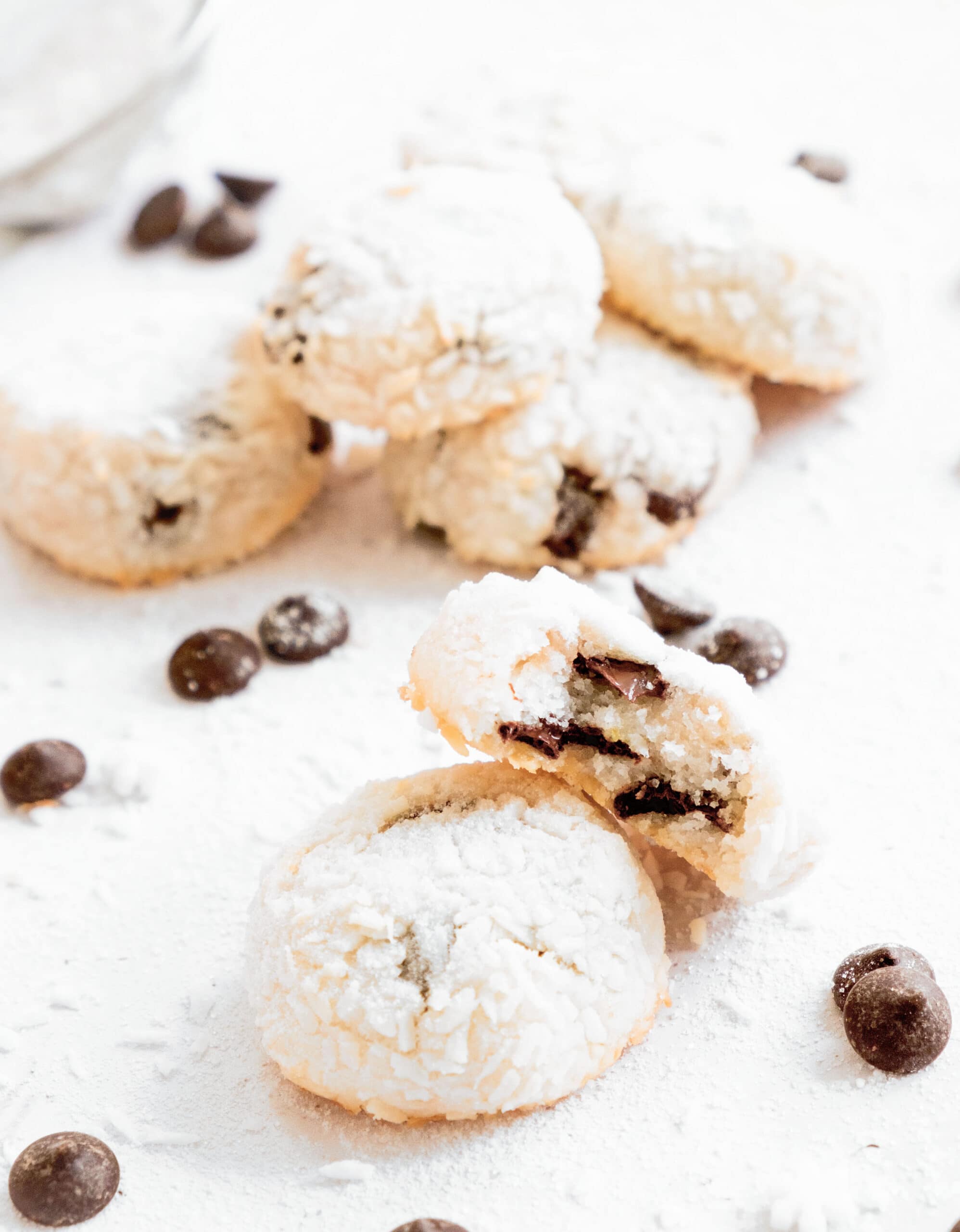 A few white and soft coconut chocolate chip cookies over a white background.