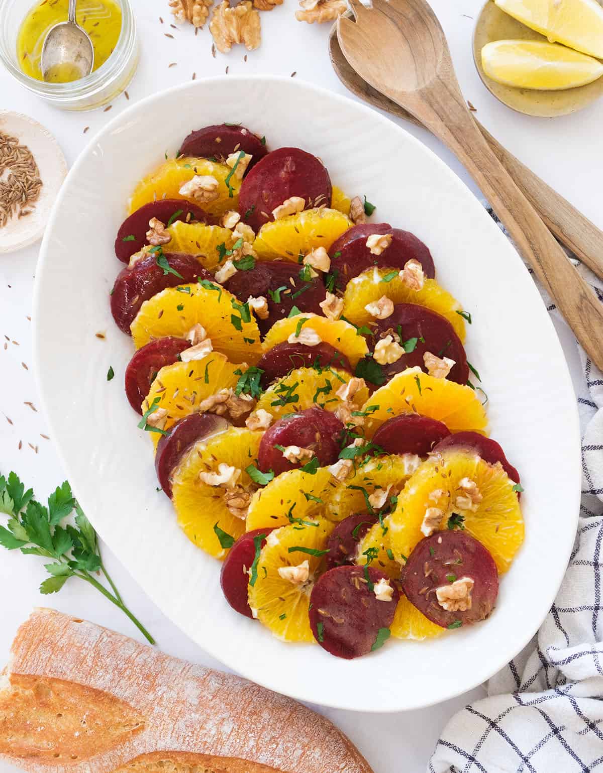 Top view of an oval white serving plate full or beetroot orange salad with walnuts. 