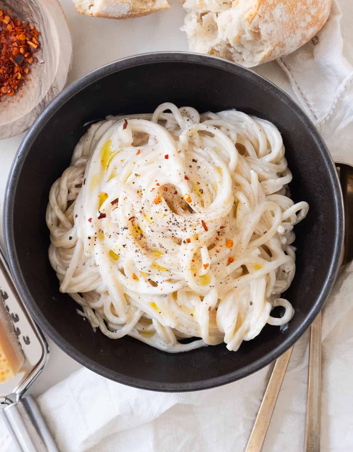 Top view of a black bowl full of creamy spaghetti.