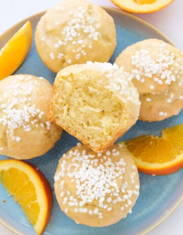 Top view of a few orange muffins over a light blue plate.