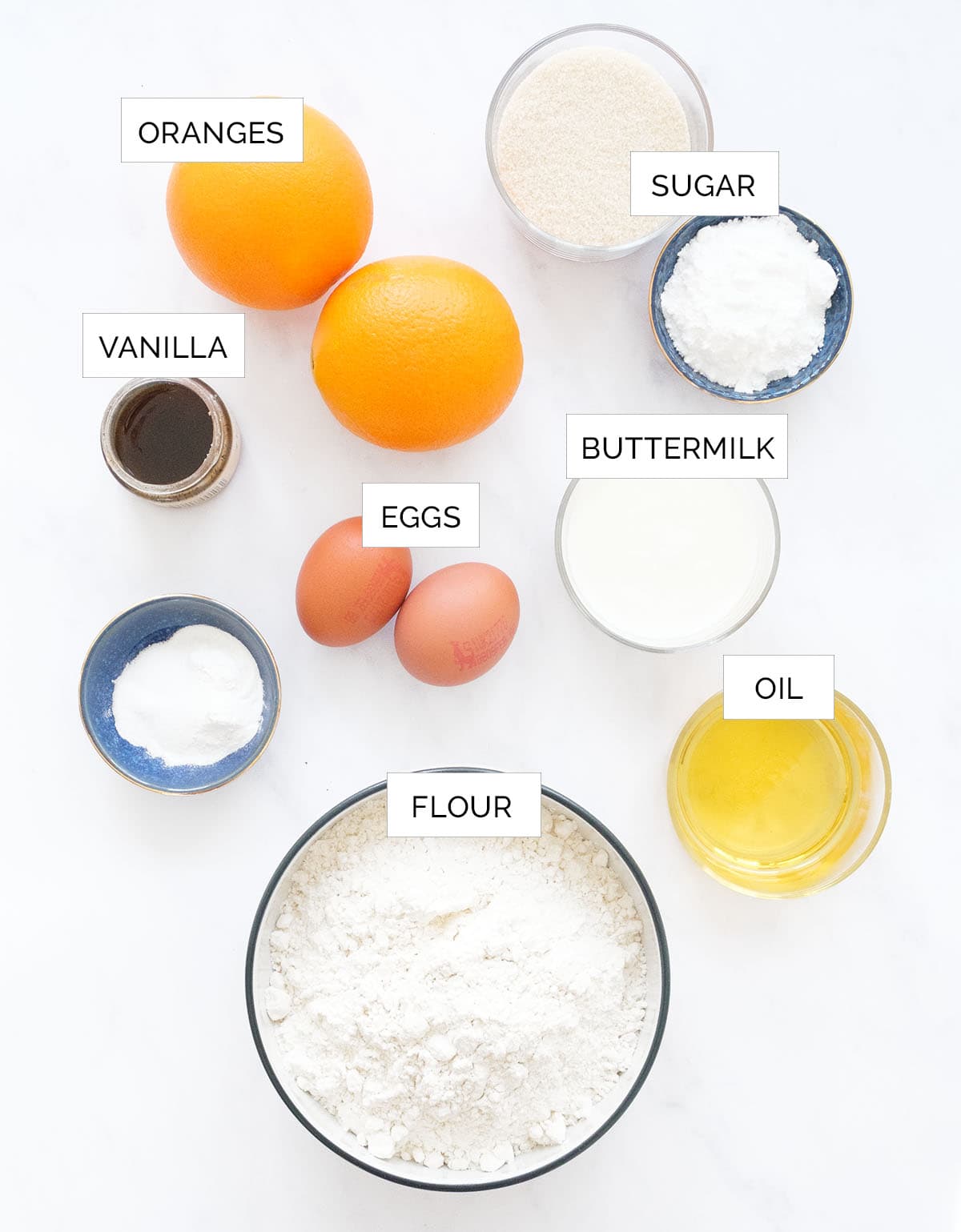 Top view of the ingredients to make orange muffins arranged over a white background.