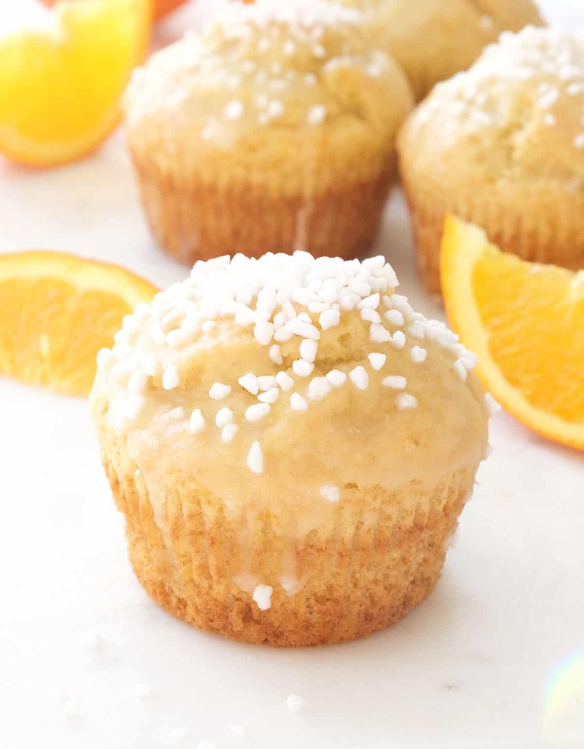 Close-up of an orange muffins with pearl sugar over a white background.