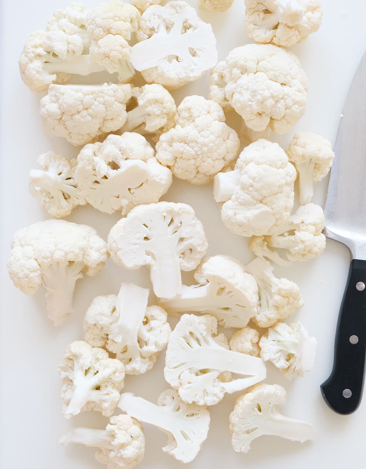 Top view of a fresh cauliflower cut into florets over a white background.