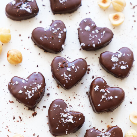 Top view of some heart-shaped vegan chocolate truffles on a white background.