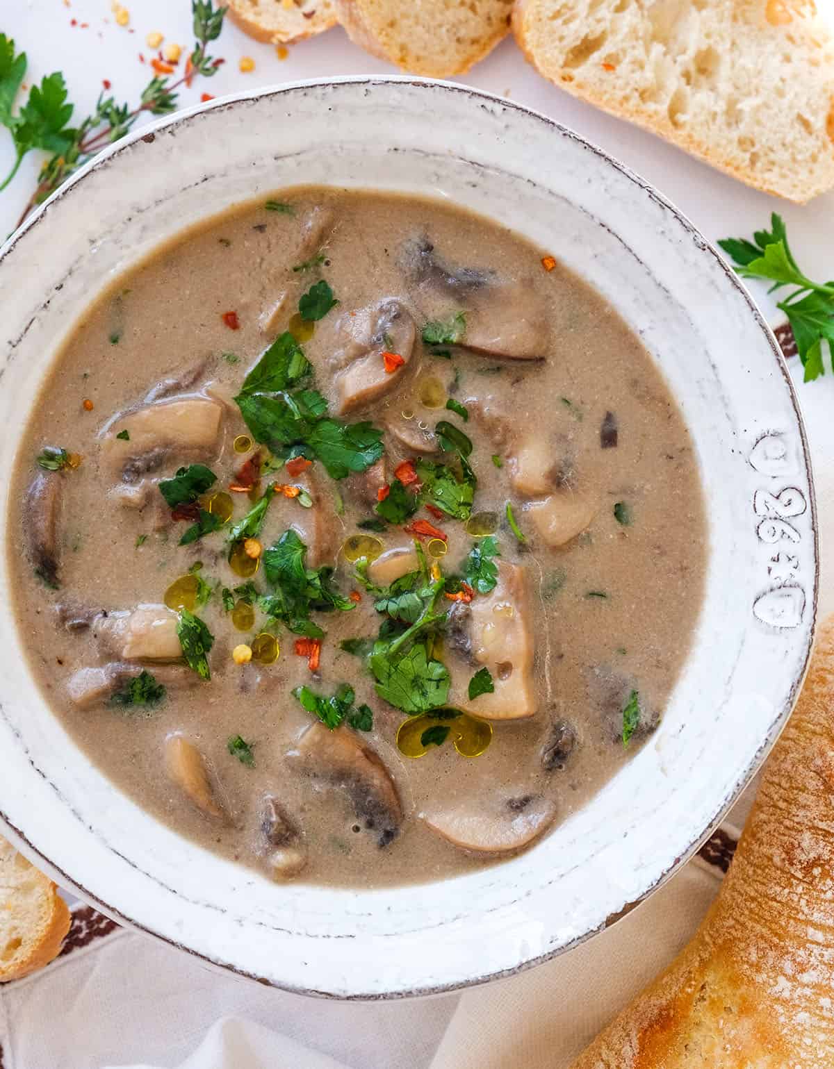 Top view of a white bowl full of creamy vegan mushroom soup garnished with parsley.
