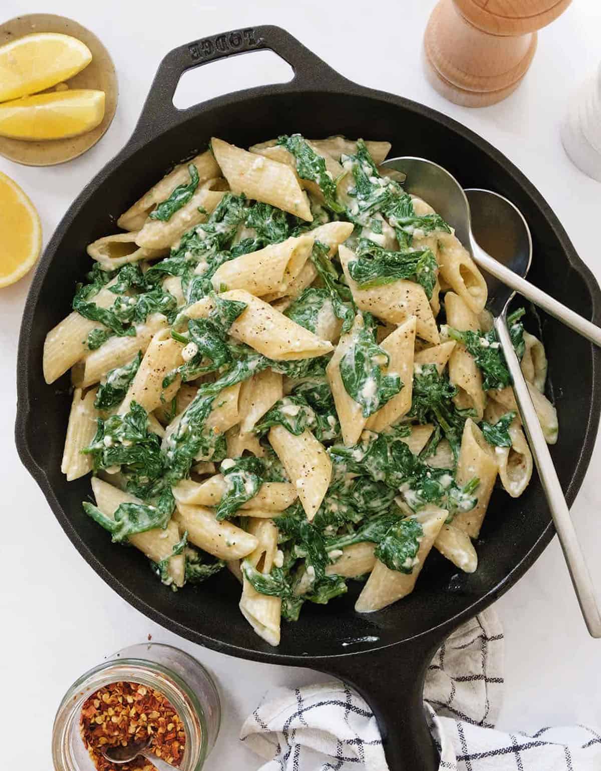 Top view of a cast iron skillet full of meatless pasta made with spinach and feta.