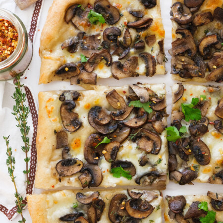 Top view of a mushroom pizza cut into slices.