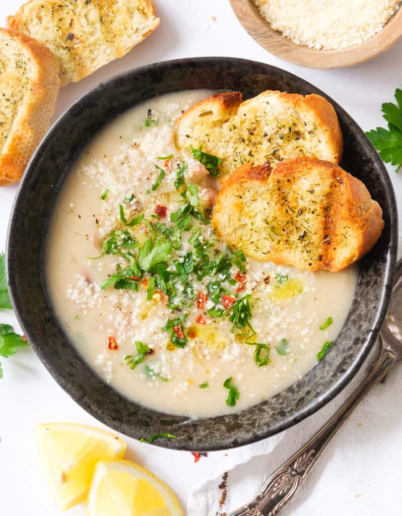 A bowl of creamy bean soup served with two slices of crusty bread.