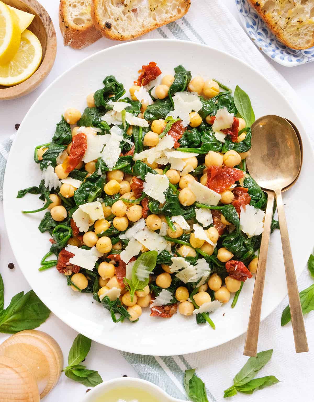 Top view of a white serving plate full of chickpea spinach salad with sundried tomatoes.