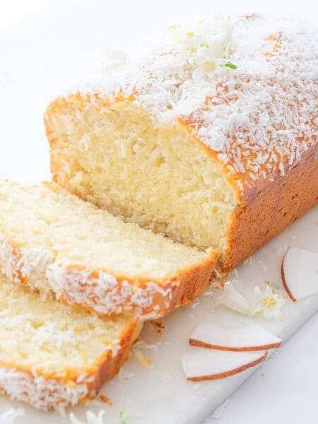 A coconut bread topped with grated coconut over a white background.