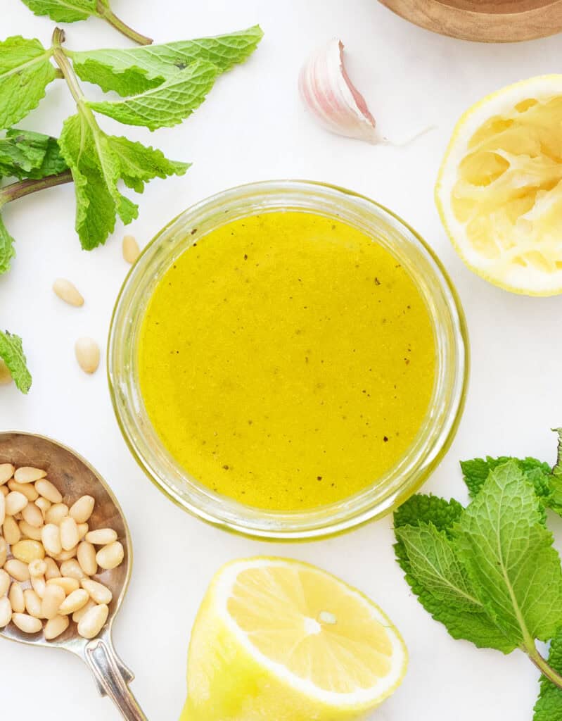 Top view of a glass jar full of lemon dressing for the fava bean salad.