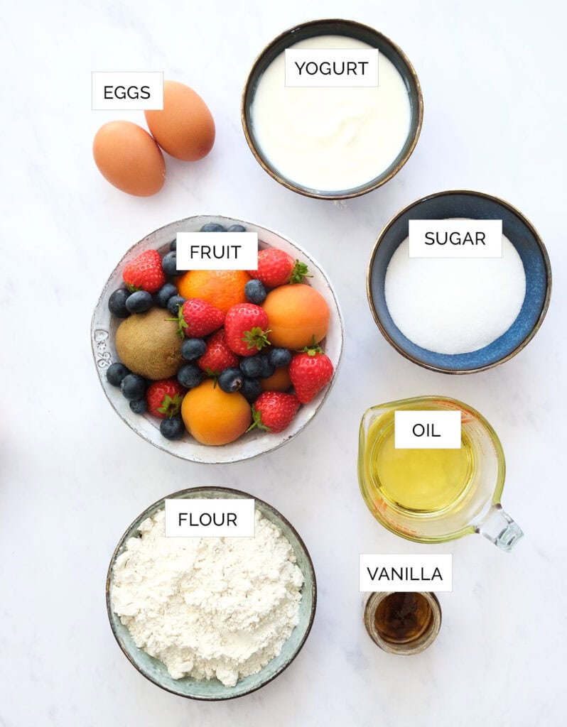 The ingredients to make this fruit cake are arranged over a white background.