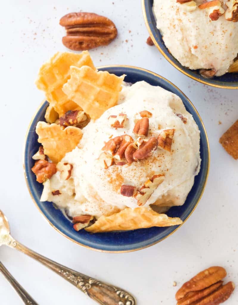 Top view of a blue bowl full of apple ice cream topped with pecans.