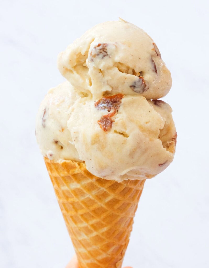A waffle cone topped with apple ice cream over a white background.