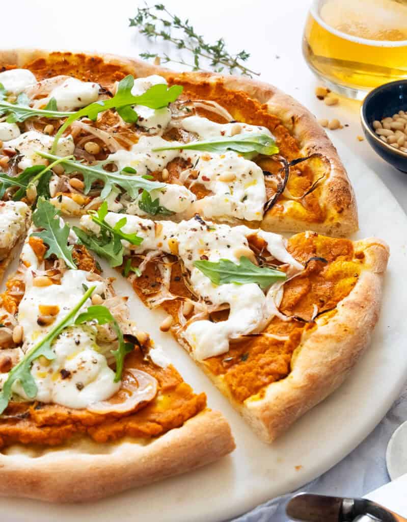 Close-up of a pumpkin pizza cut into slices.