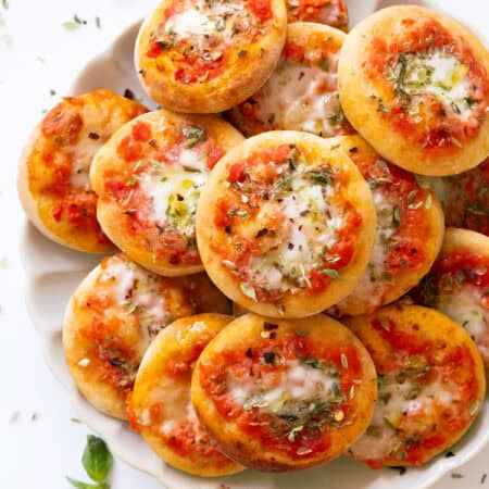 Top view of a plate full of small pizzas.