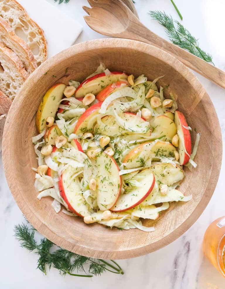 Top view of a wooden bowl full of fennel and apple salad.