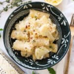 Top view of a dark bowl full of pasta with cauliflower.