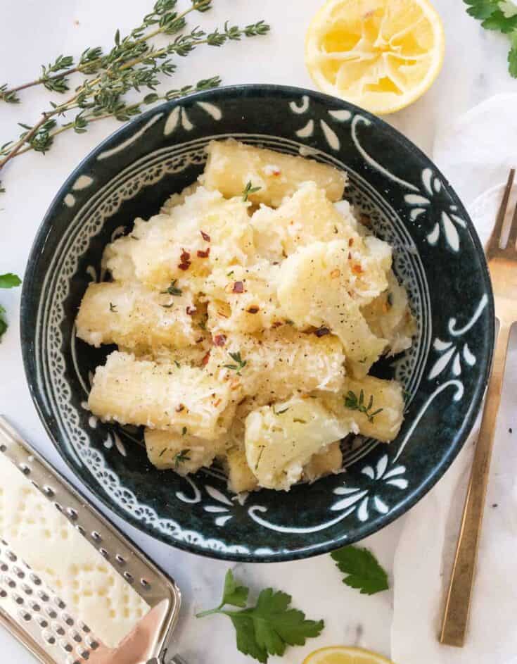 Top view of a dark bowl full of pasta with cauliflower.