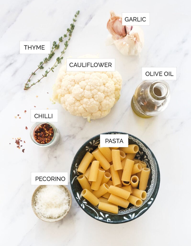 The ingredients to make pasta with cauliflower are arranged over a white background.