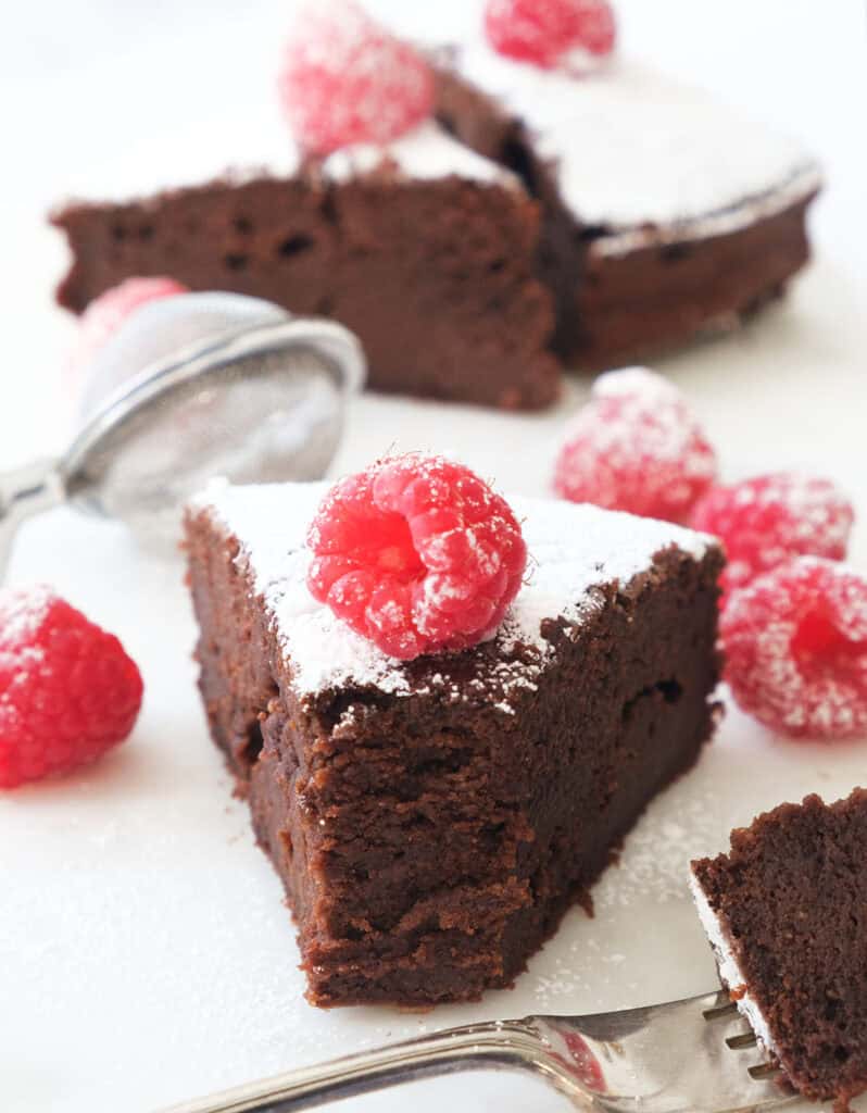 Close-up or a slice of a moist chocolate ricotta cake topped with a raspberry.
