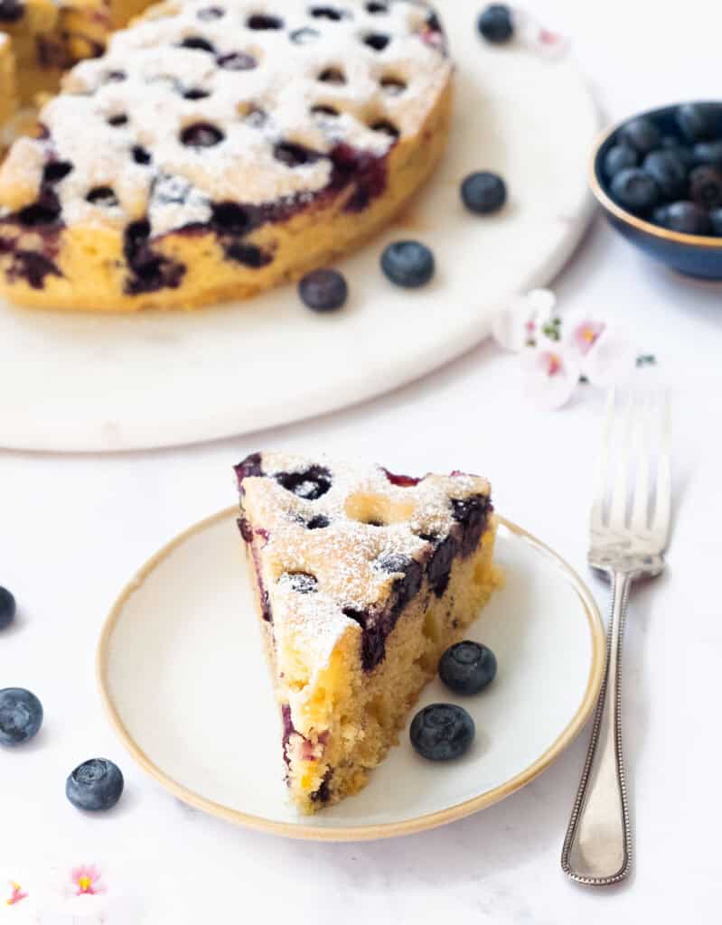 A slice of ricotta blueberry cake on a white plate.