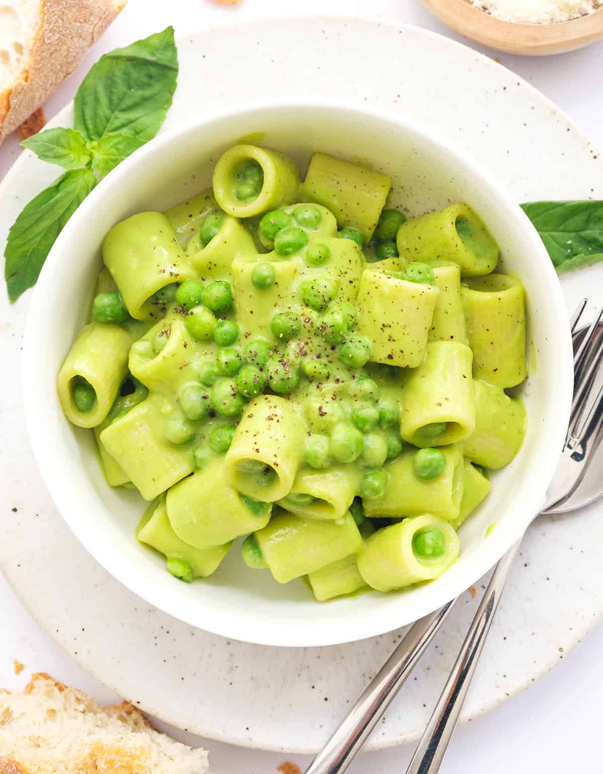 Top view of a whtie bowl full of creamy pea pasta.
