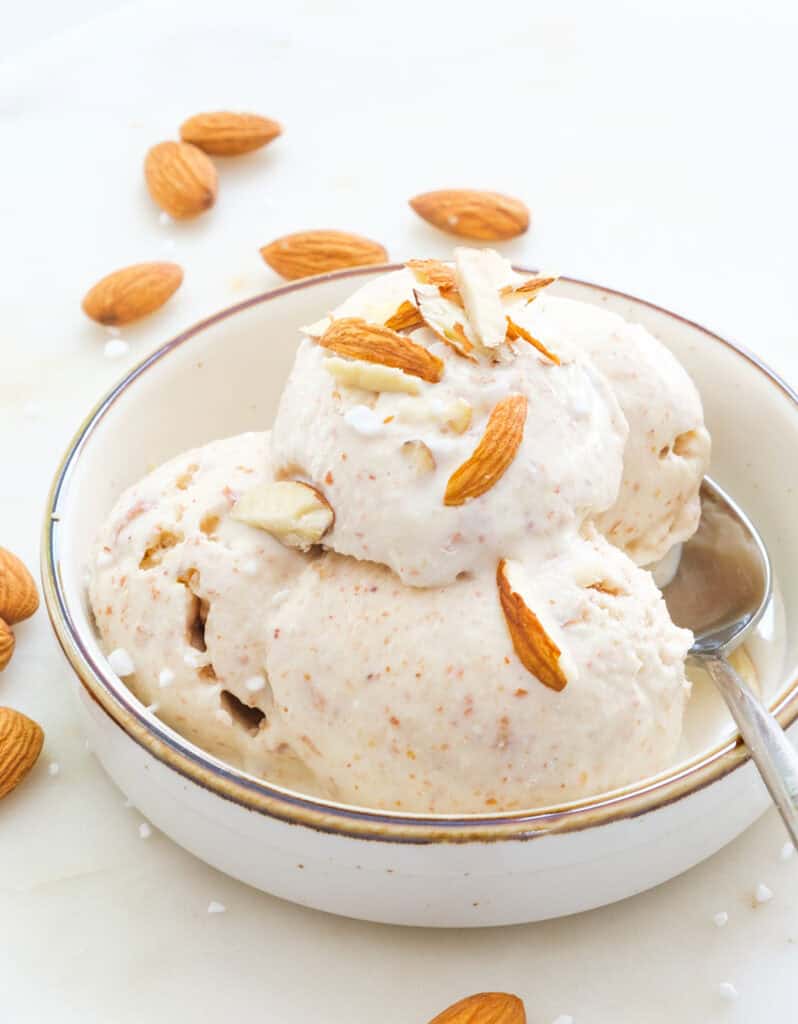Scoops of almond ice cream served in a bowl and topped with sliced almonds.