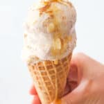 Close-up of a cone topped with almond ice cream over a white background.