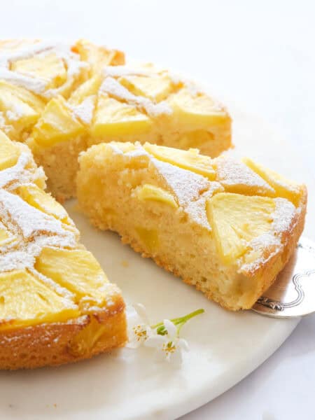 Close-up of a slice of pineapple cake over a white background.