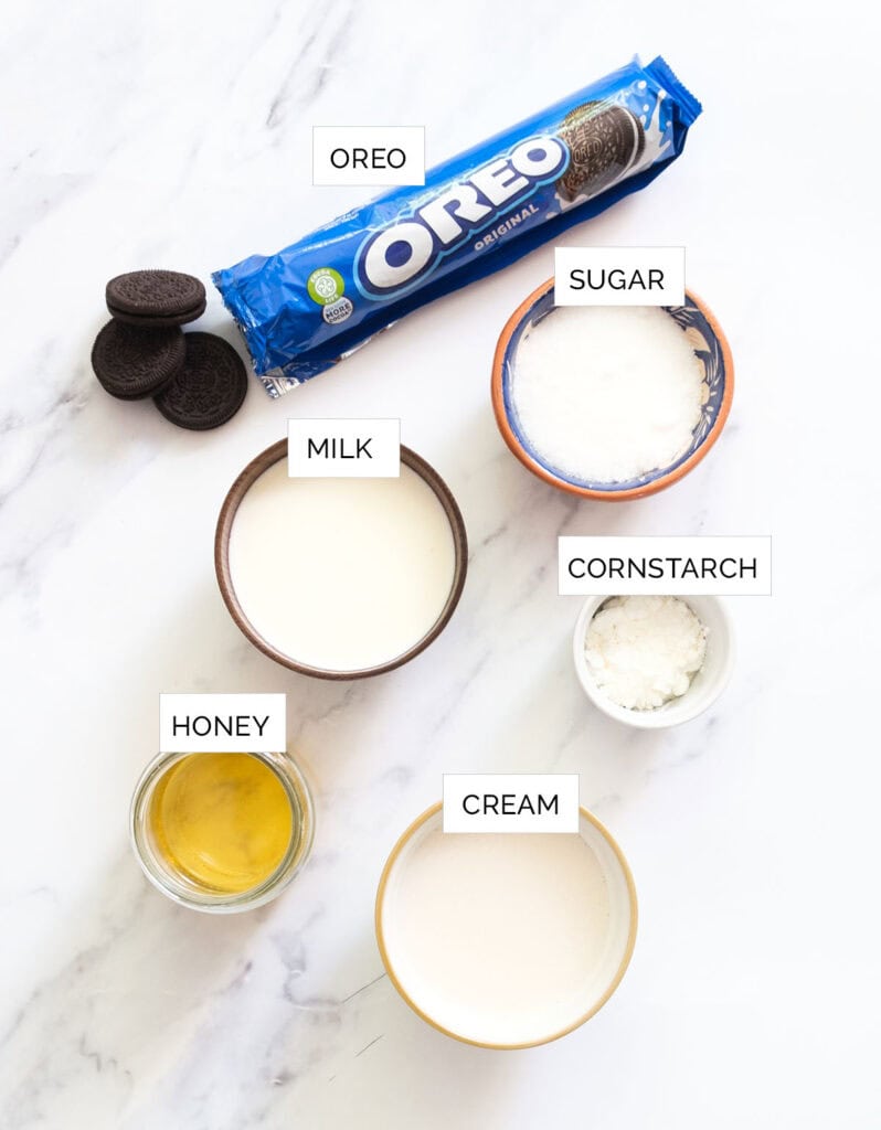 The ingredients to make oreo ice cream are arranged over a white background.