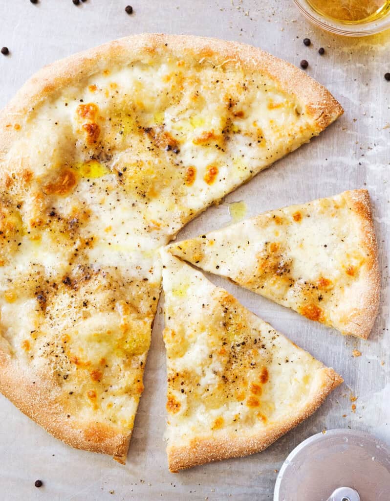 Top view of a cacio e pepe pizza drizzled with olive oil.