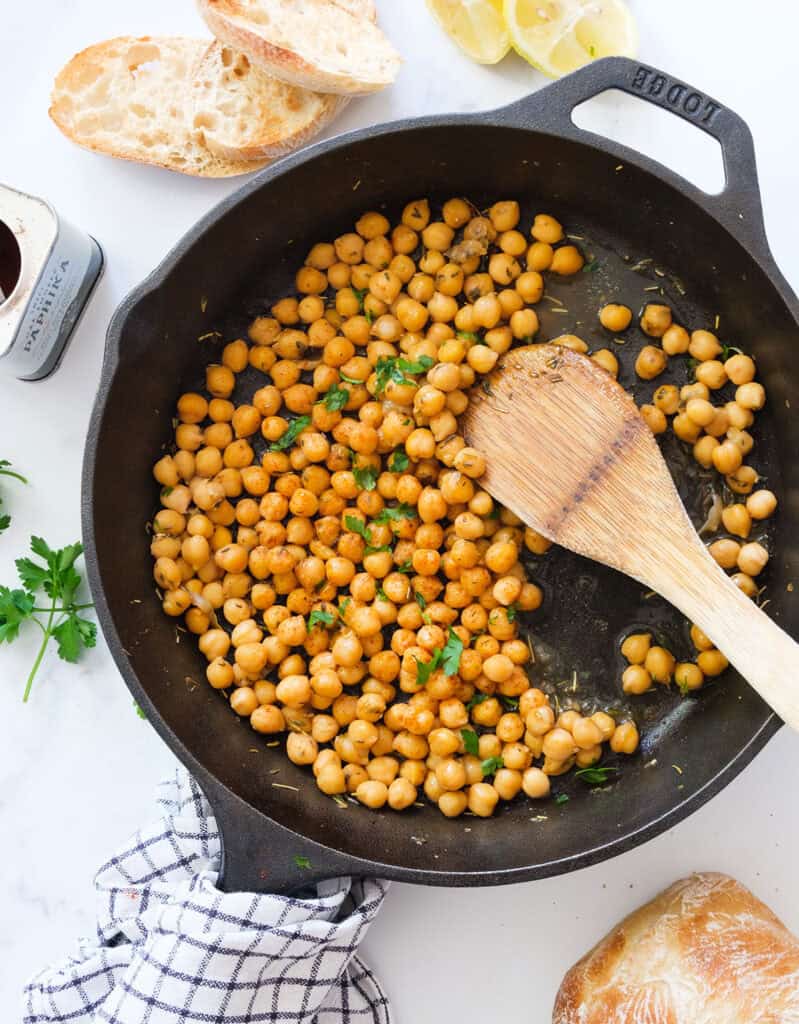Top view of a cast iron skillet with sauteed chickpeas.