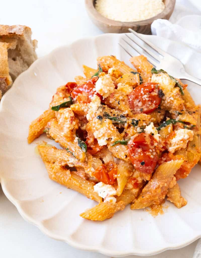 Close-up of a portiton of tomato ricotta pasta on a white plate.