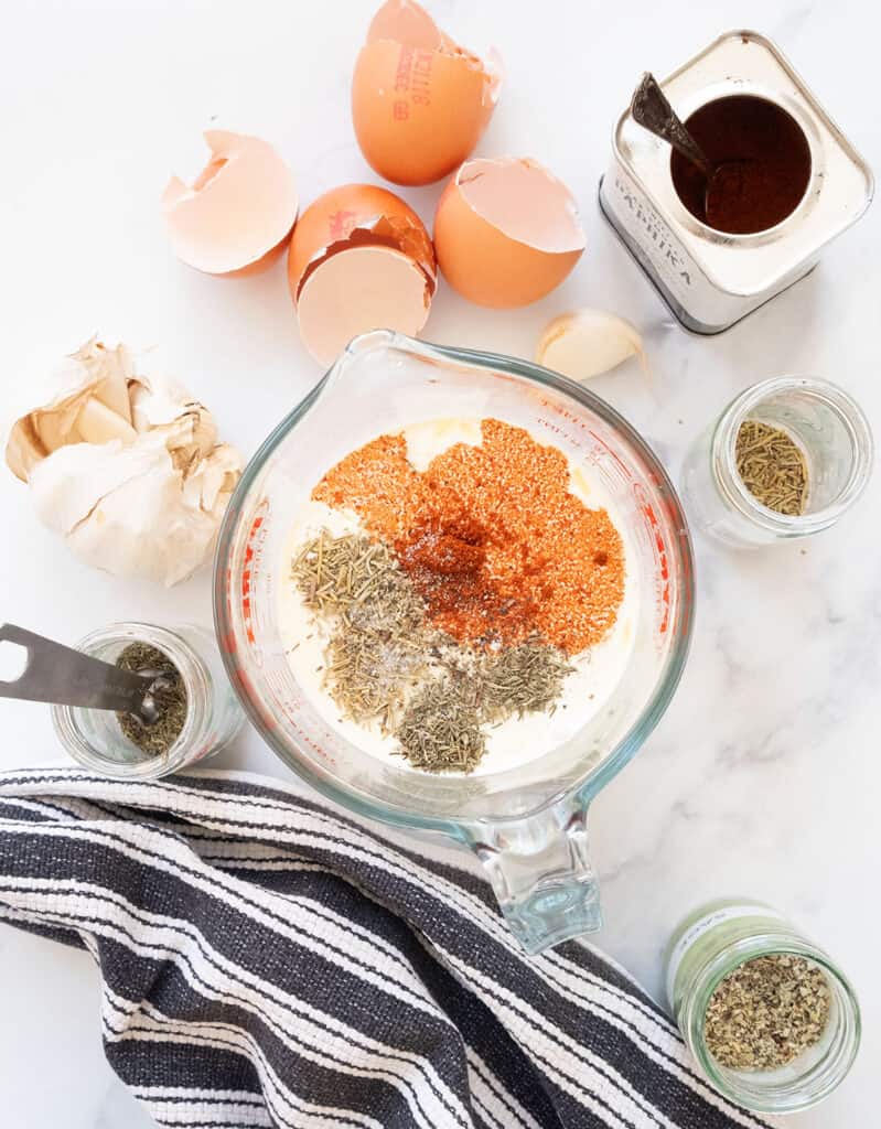 Top view of a jug full of milk, herbs, and paprika.