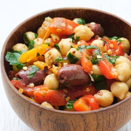 Close-up of a bowl full of easy chickpea salad over a white background.