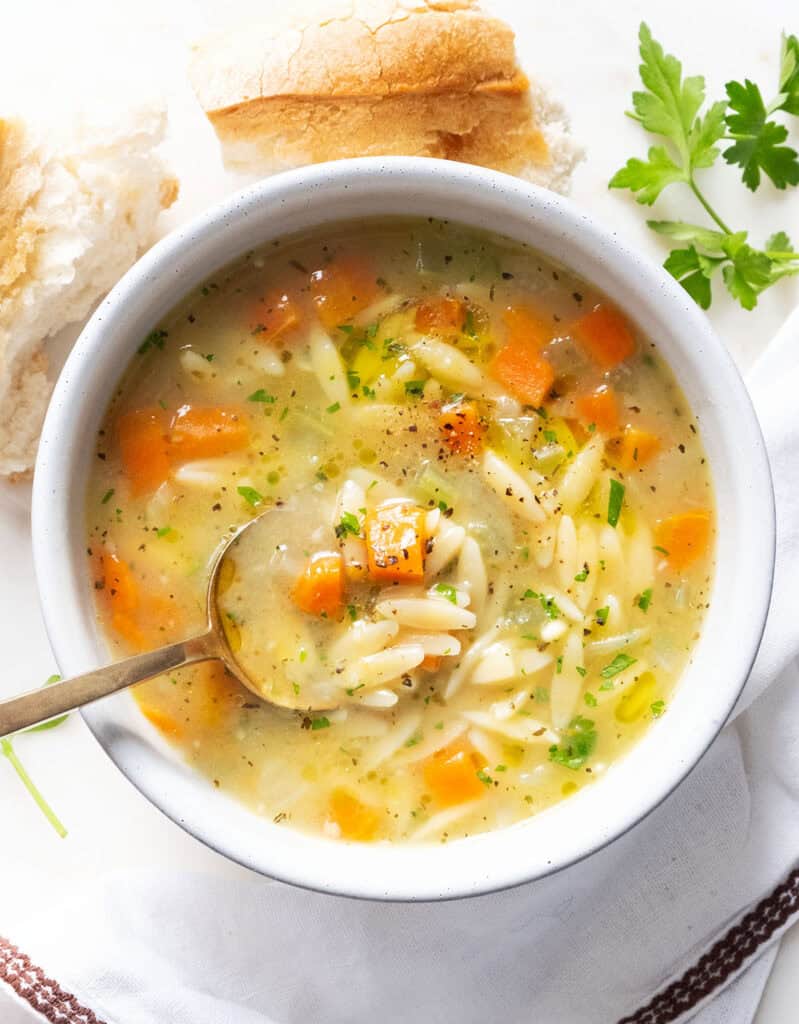 Top view of a white bowl full of orzo soup.