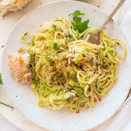 Top view of a serving of cabbage pasta on a white plate.