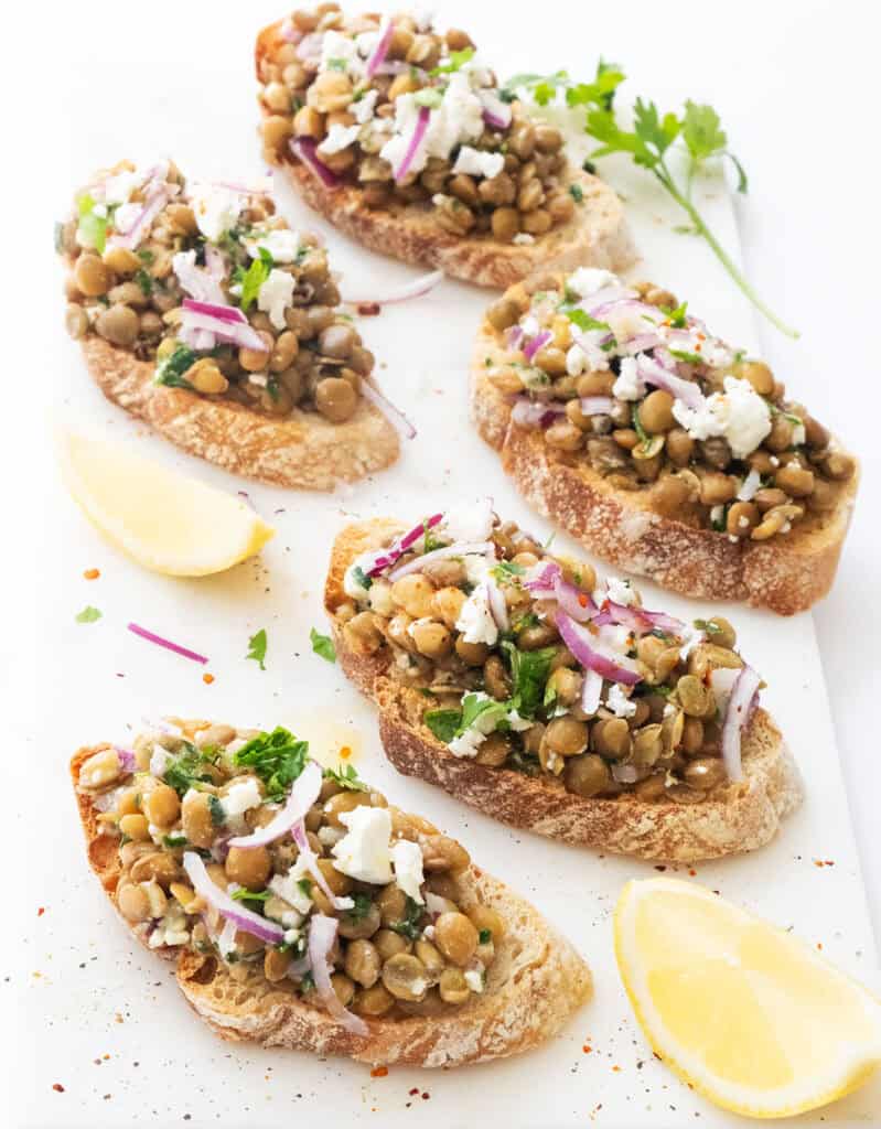 Lentil bruschetta over a white background.